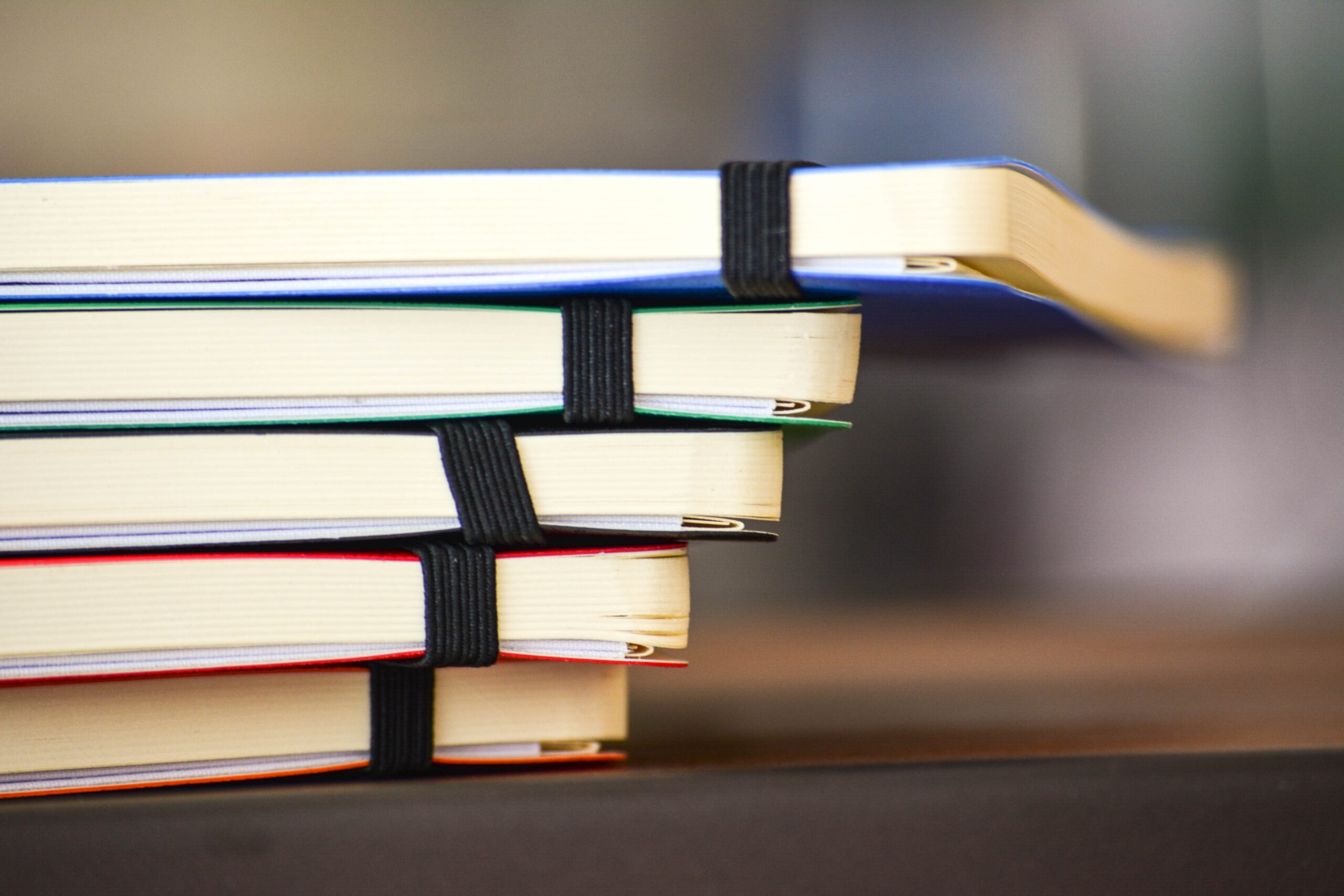 A stack of five coloured notebooks